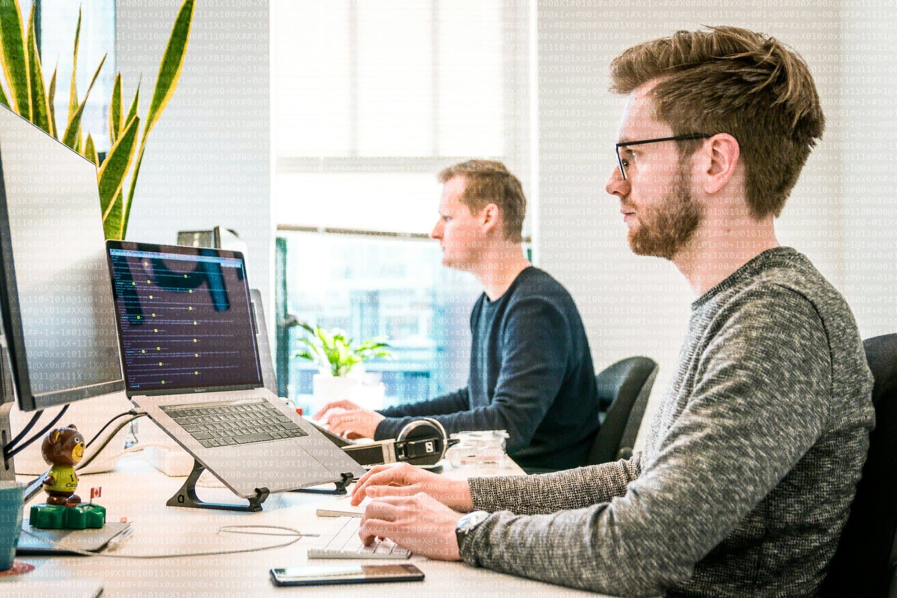 Dos desarrolladores trabajando con monitores en una oficina luminosa