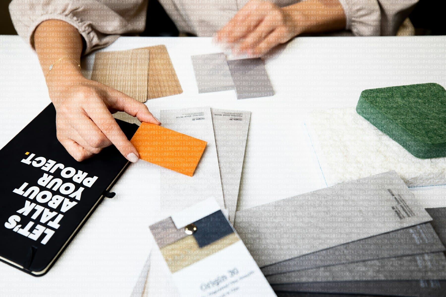 Manos eligiendo muestras de materiales y color sobre una mesa blanca