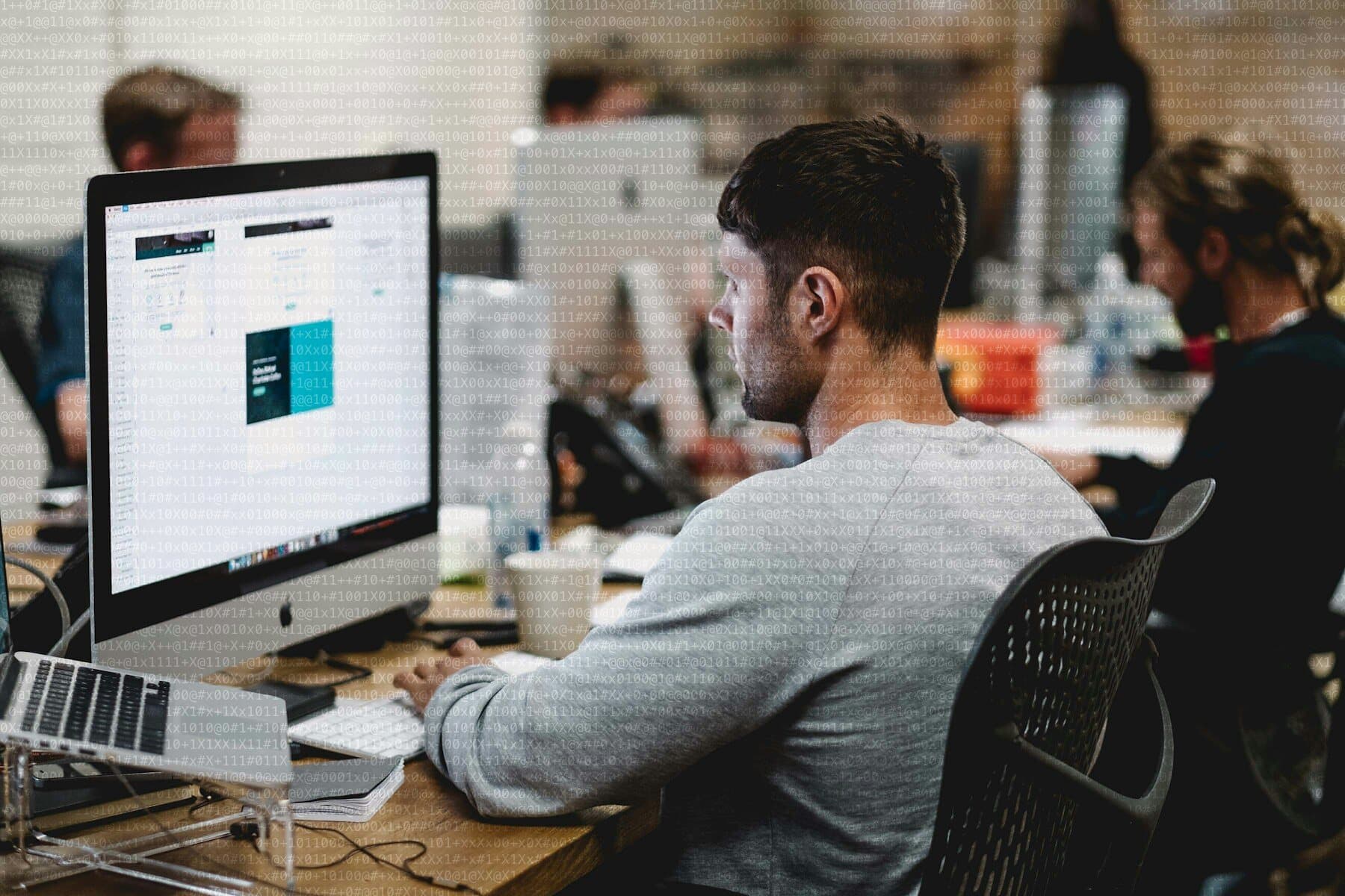Diseñador trabajando en una interfaz en un iMac dentro de un estudio