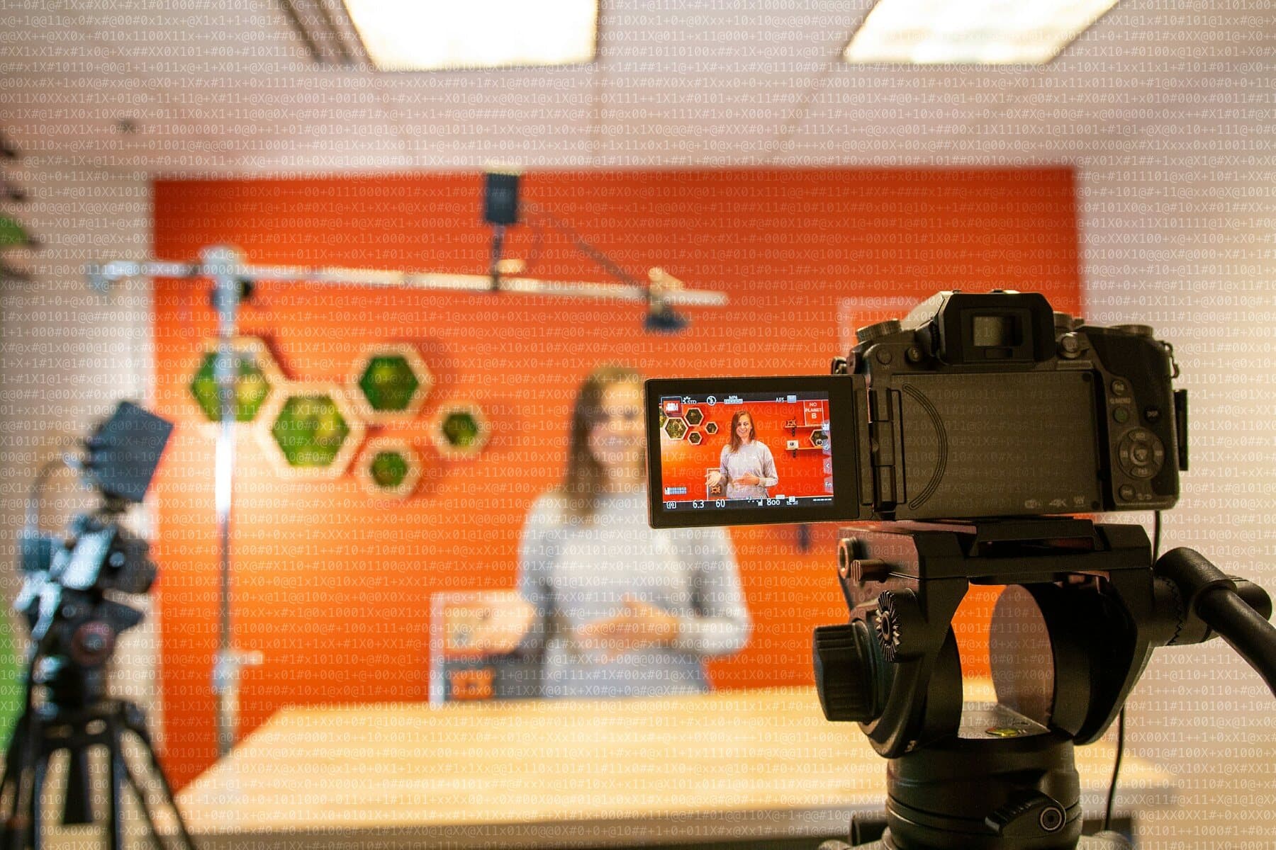 Cámara grabando a una presentadora en un plató con pared naranja